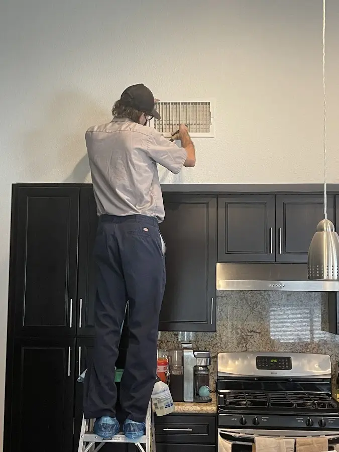 Technician inspecting an air vent during HVAC service in San Leandro